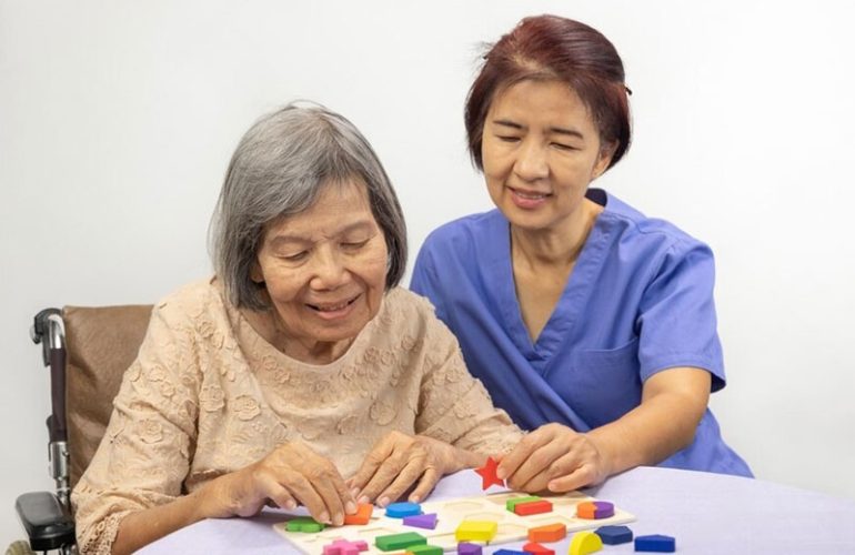 caregiver senior woman playing wooden shape puzzles game dementia prevention